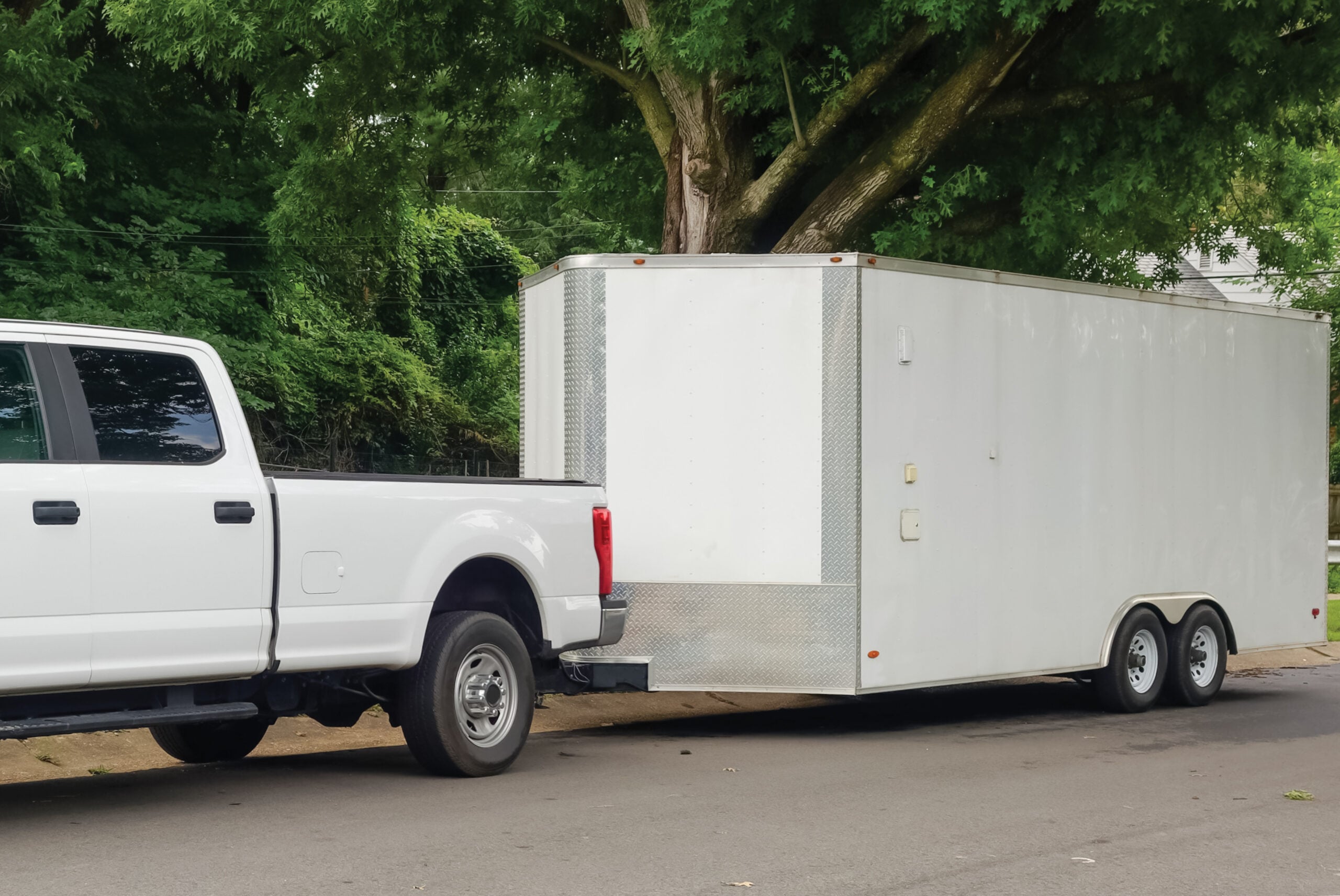 White cargo trailer hitched to a white pickup truck